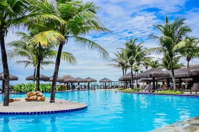Palm trees and loungers beside a sunny beachfront resort pool