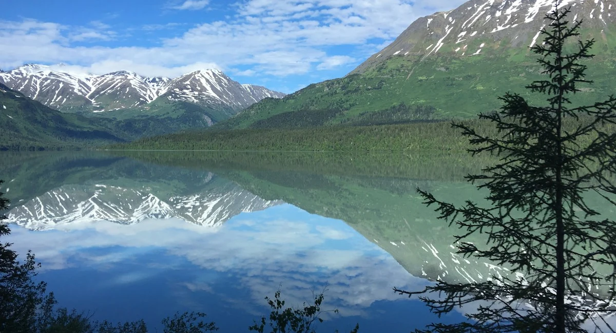 Snow-capped Alaskan mountains reflected in a blue lake