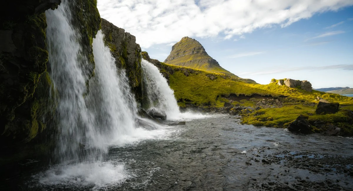 Kirkjufellsfoss waterfall and green hills in Iceland